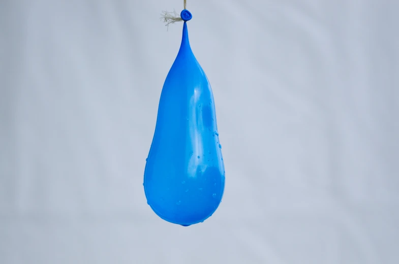 a single blue drop of water suspended by a wire