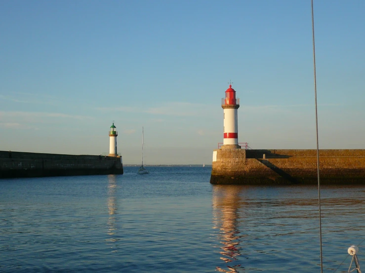 two sailboats on a body of water near a lighthouse