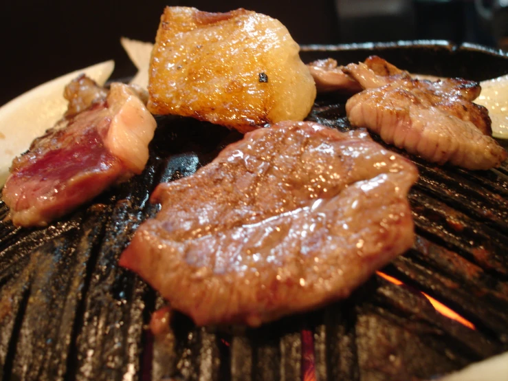 a barbecue grill with meat and potatoes on it