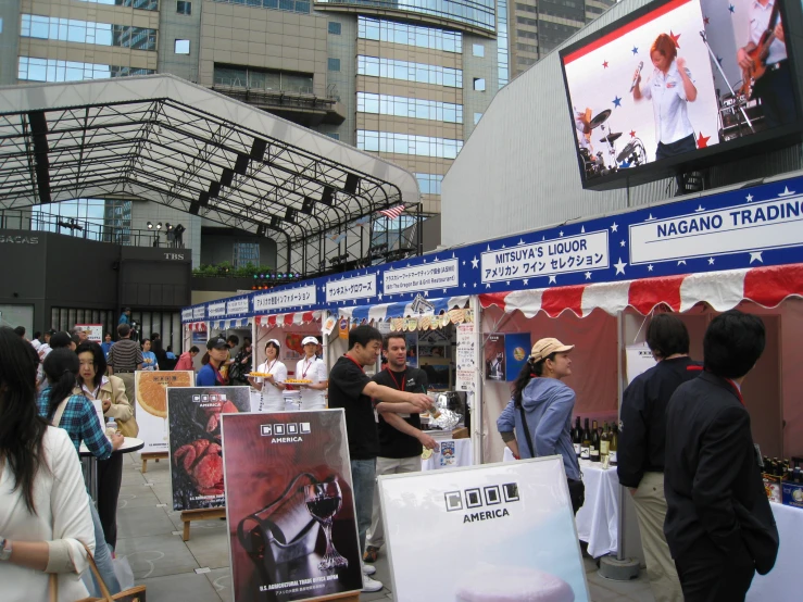 people are gathered at a trade stand and some have tvs on display