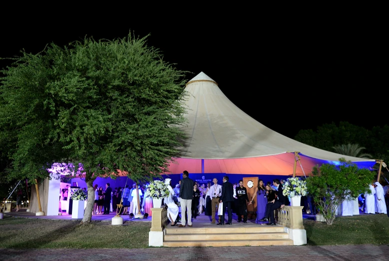 a group of people posing in front of a tent at night