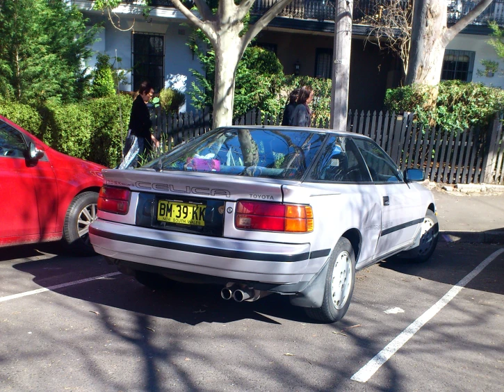 the rear end of a car is parked beside another red car