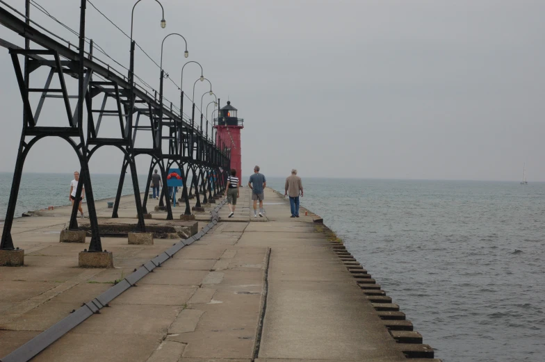 three people walk next to the pier looking at the water