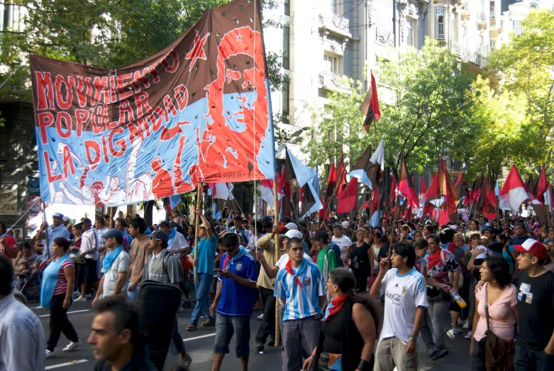 people marching down a street carrying red and blue flags