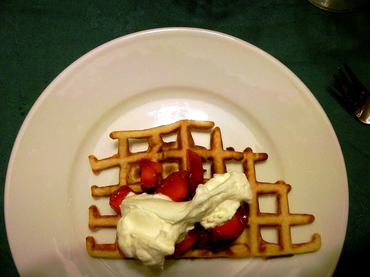 the waffle on the plate has some whipped cream on it