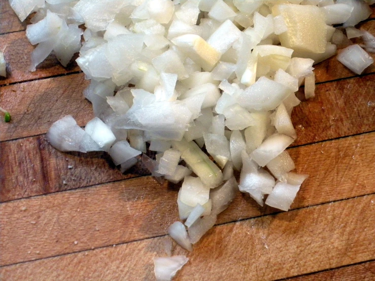 onions being chopped on a wooden  board