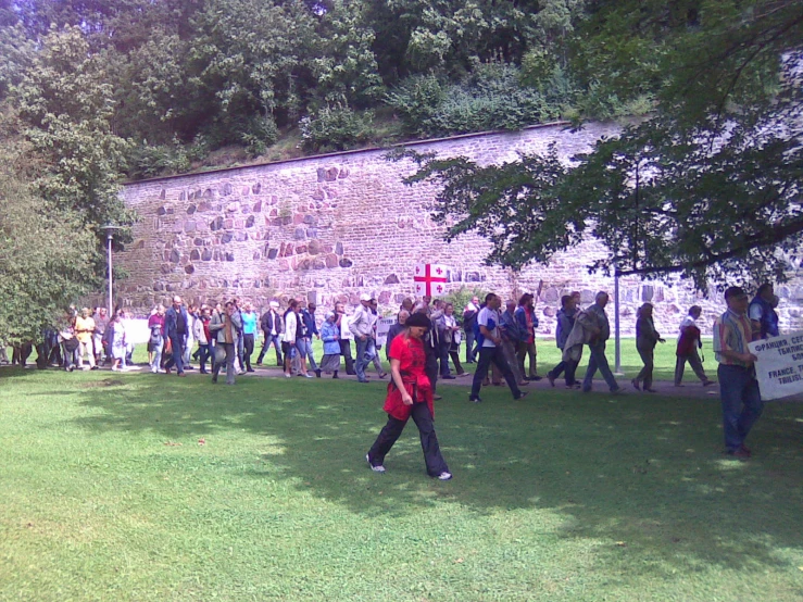 several people are standing in the grass by a stone building