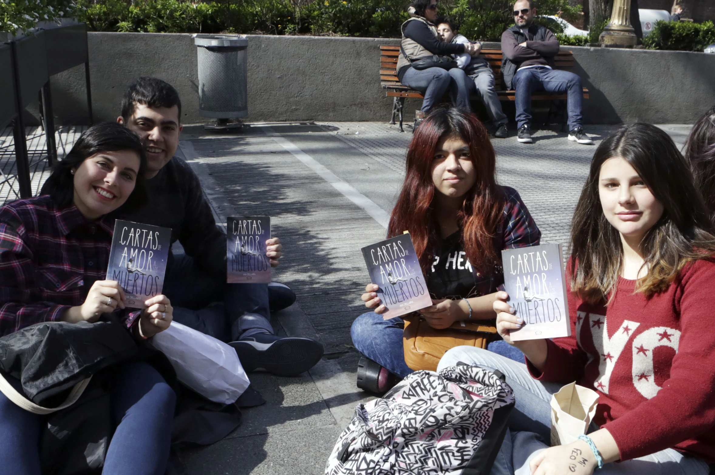 the four young people are sitting together on the cement