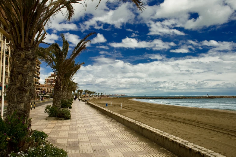 a sidewalk leads to the ocean in front of a beach