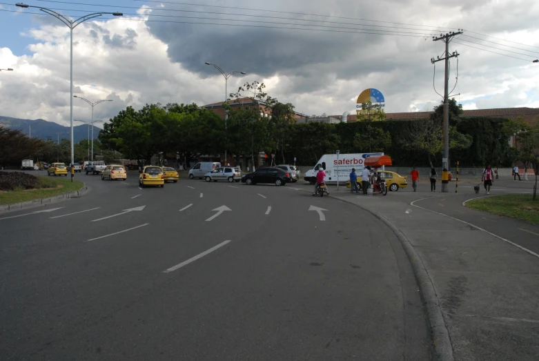 a bunch of cars on a road under cloudy skies