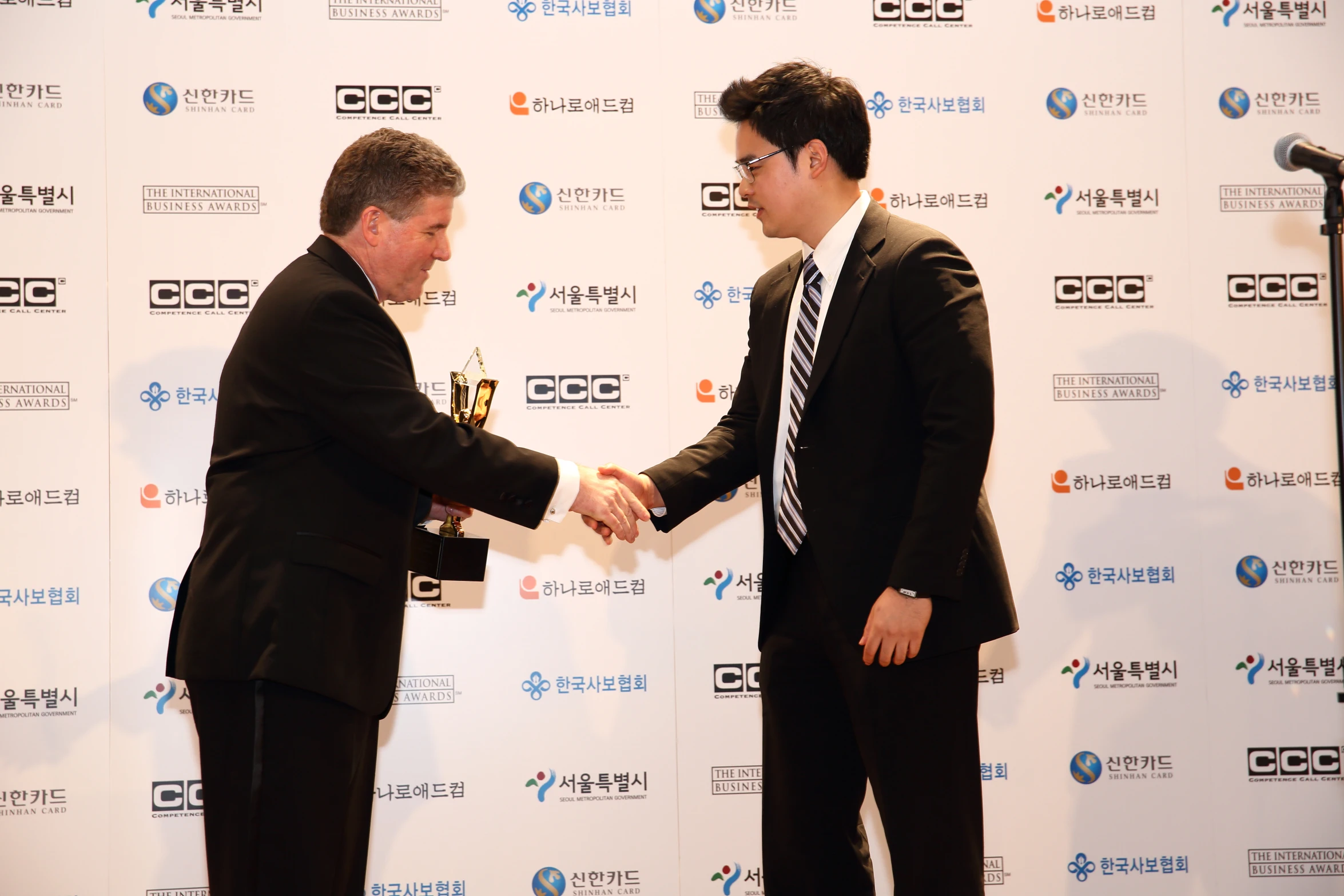 two men in suits standing holding an award