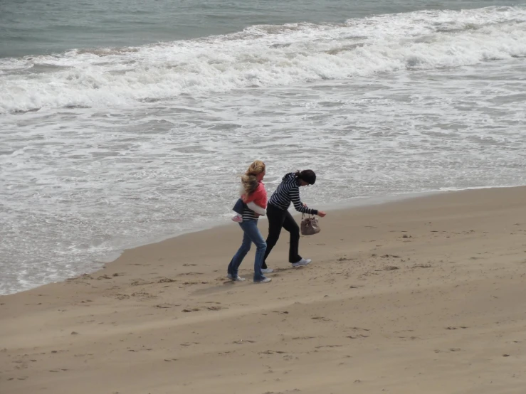 two young people are walking on the beach