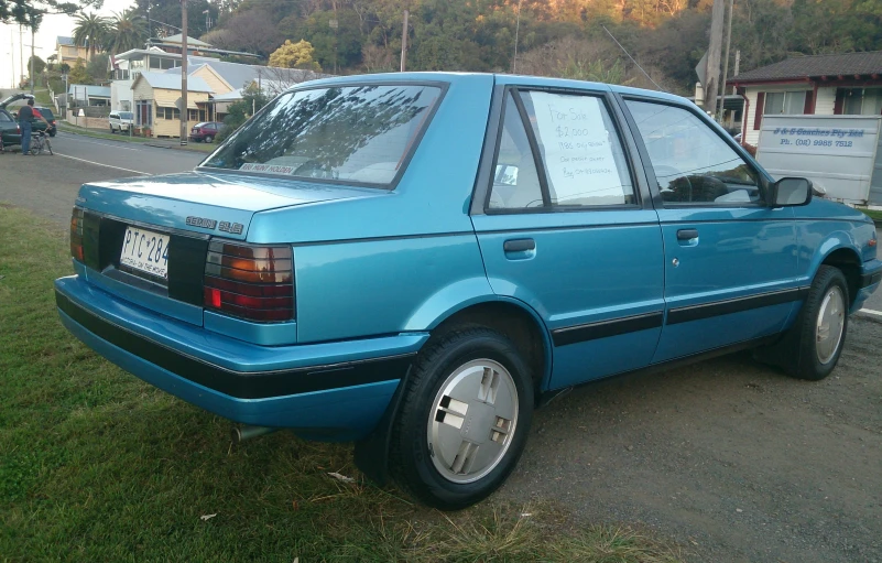 a light blue car parked on a grass covered street