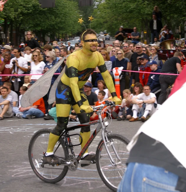 man in bee costume riding bike in a parade