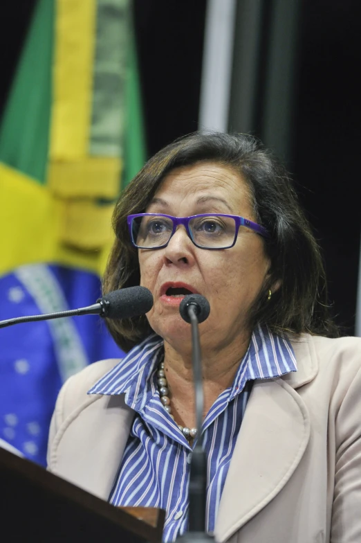 a woman is at a podium wearing glasses and a suit