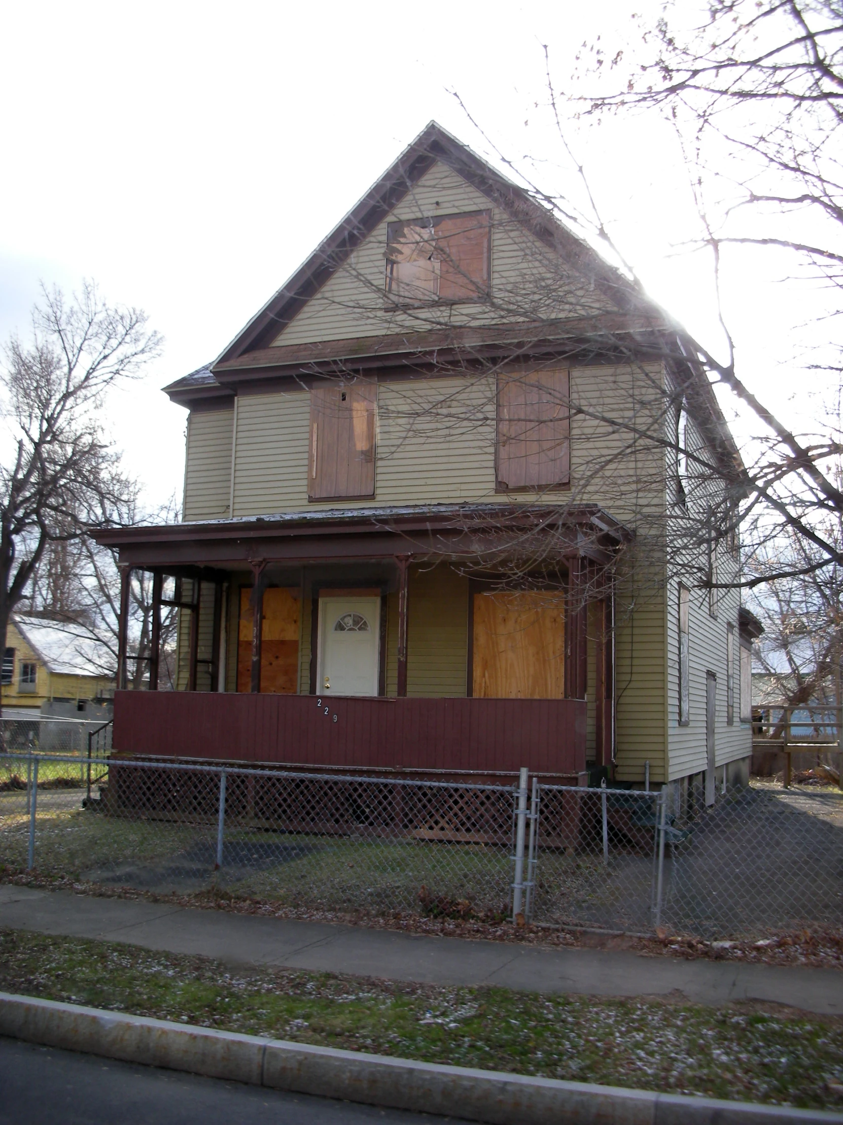 a yellow house is sitting behind a chain link fence