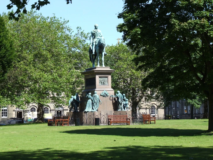 the park with many benches is in front of a statue