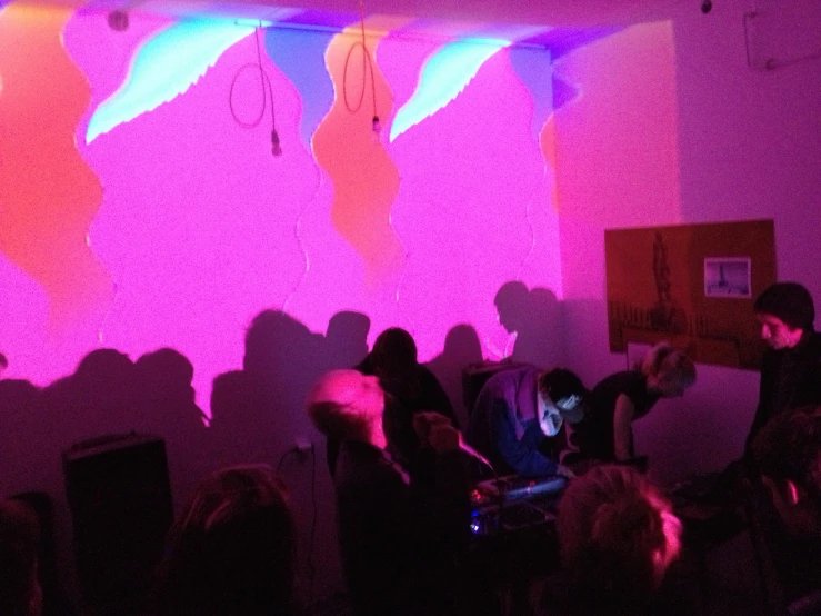 several people in silhouette against a pink wall