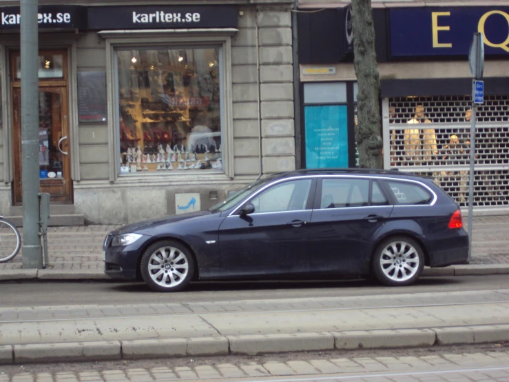 the black car parked outside of the shop is waiting