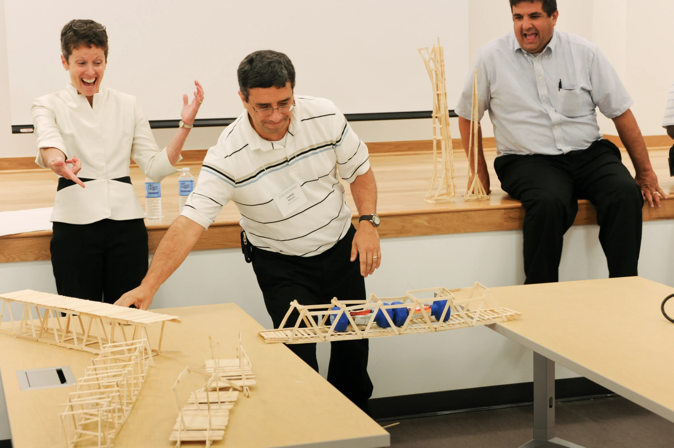 three men standing around a model with people standing around