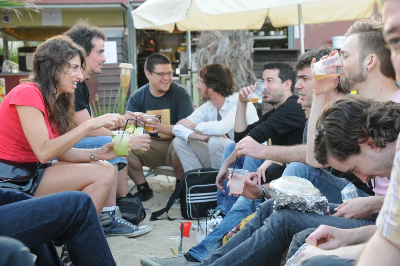 many people are sitting in chairs eating food and drinking beer