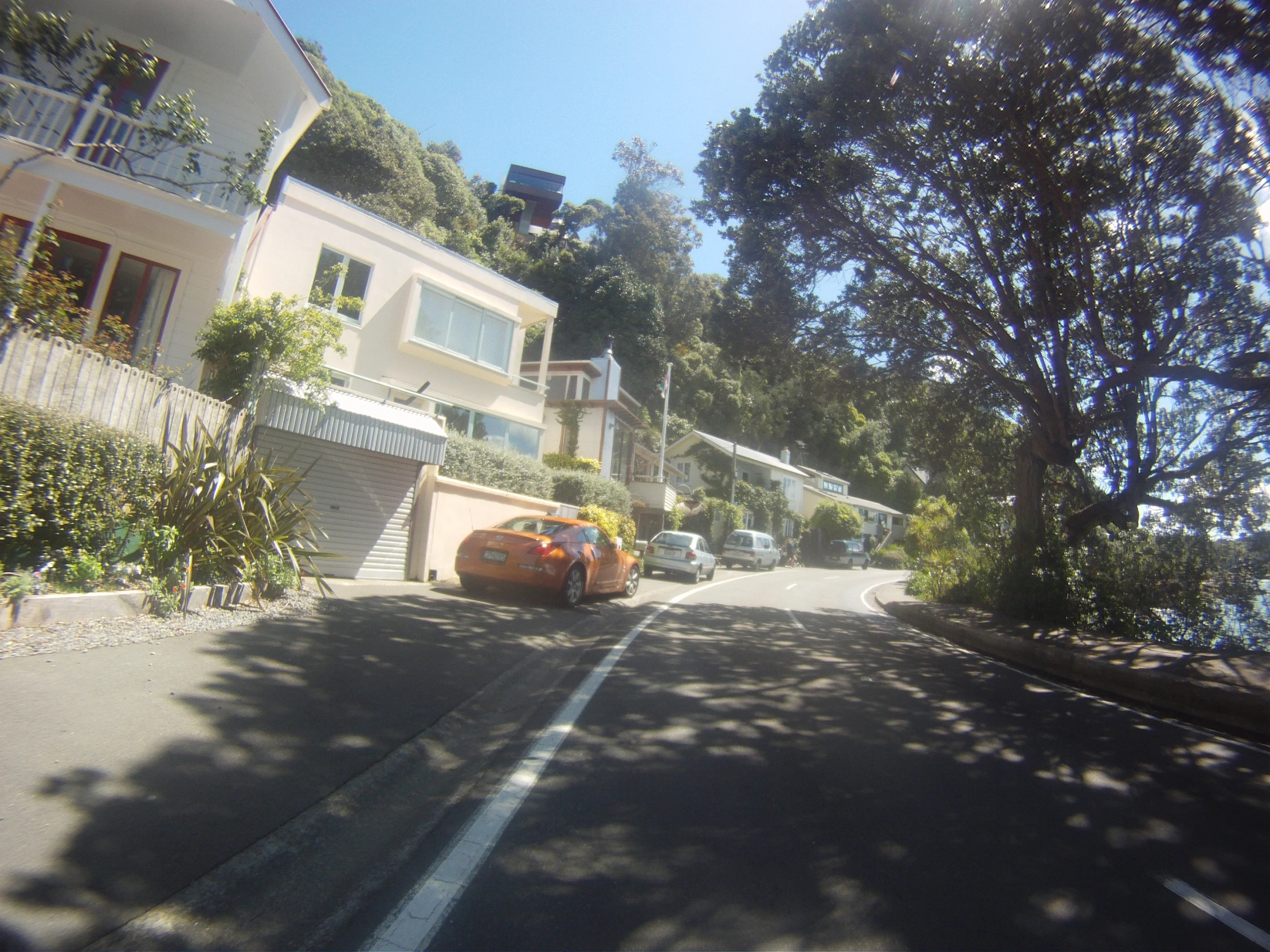 cars traveling down a residential street in the afternoon