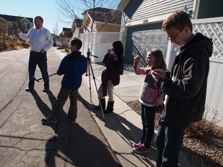 several children with skis are standing on the sidewalk