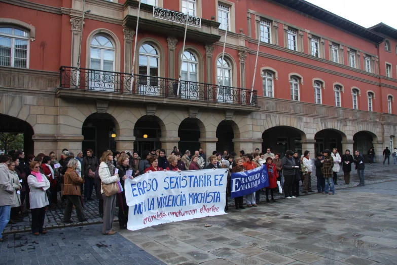 a group of people standing outside a building with a sign