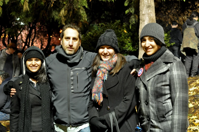 several people standing close together in front of a large group of trees