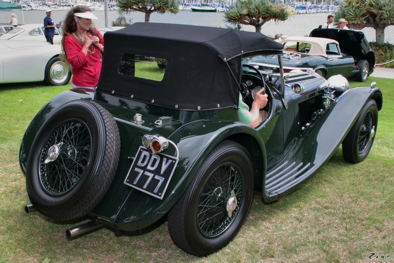 an older model car with a young lady on it's phone