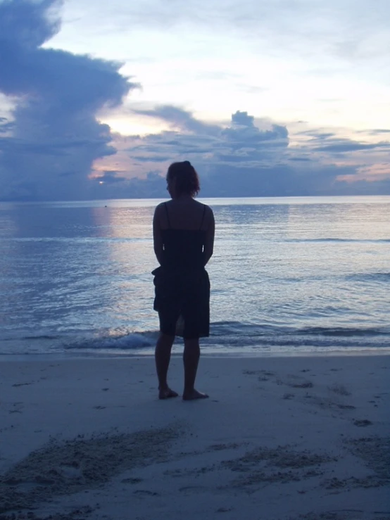 person standing alone on a beach looking out to sea