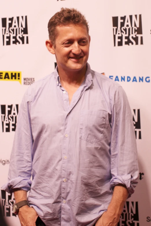 a man standing in front of a white wall and wearing glasses