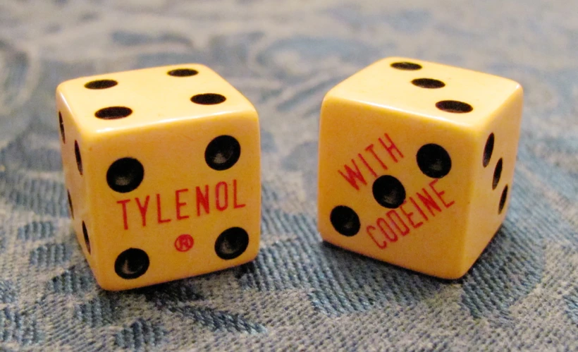 two yellow dices with the words tylenol and colo - line written on each side