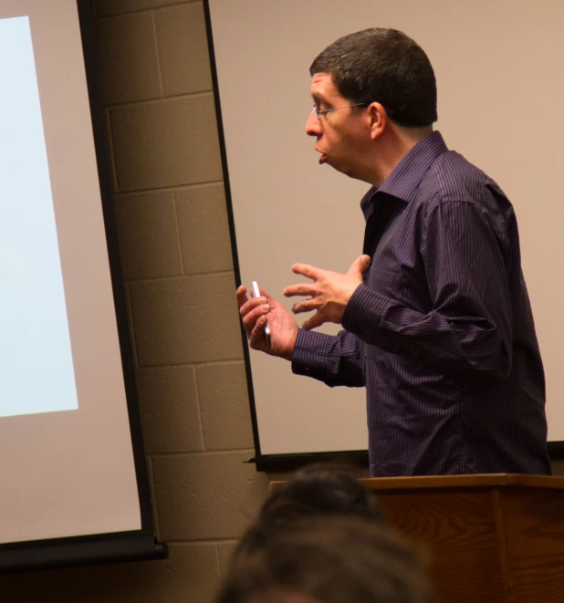 a man standing in front of a projection screen with a slider