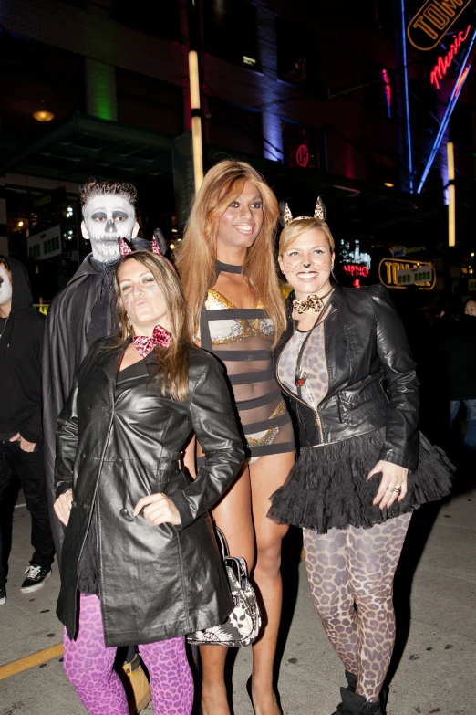 three beautiful women dressed in  costumes standing in the middle of a street