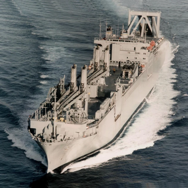 an old military ship on the water close to shore