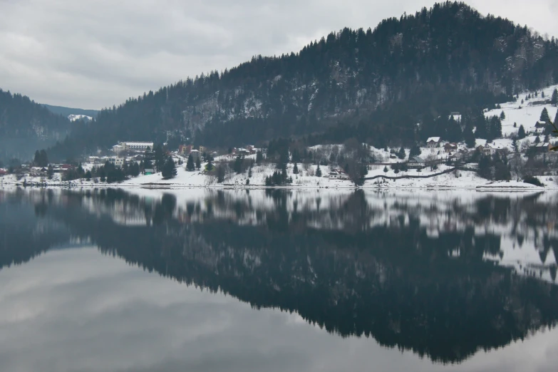 the water has little snow on it in a forested area