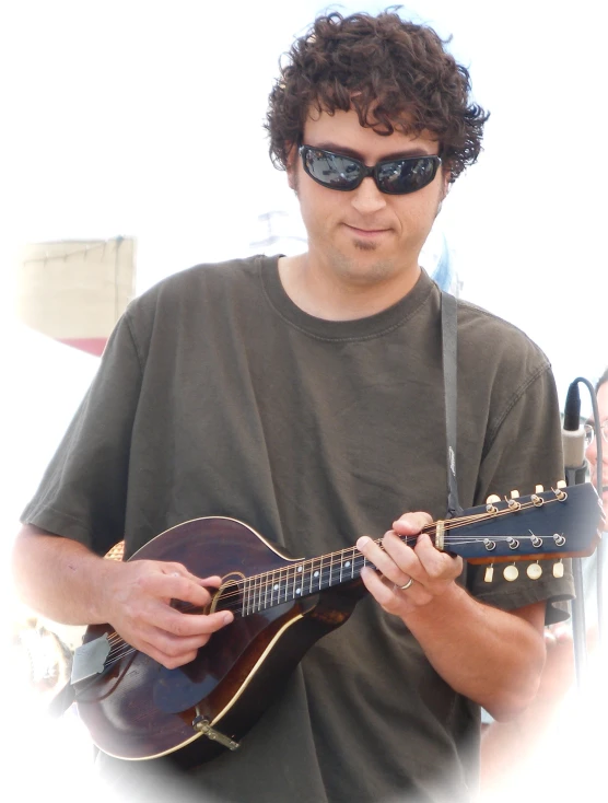 a man in sunglasses and black glasses holding a guitar