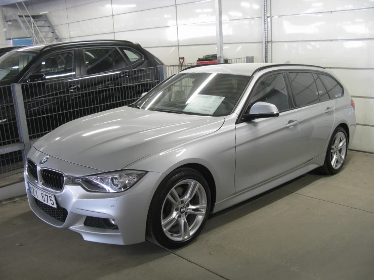 a shiny silver bmw is parked next to a black bmw