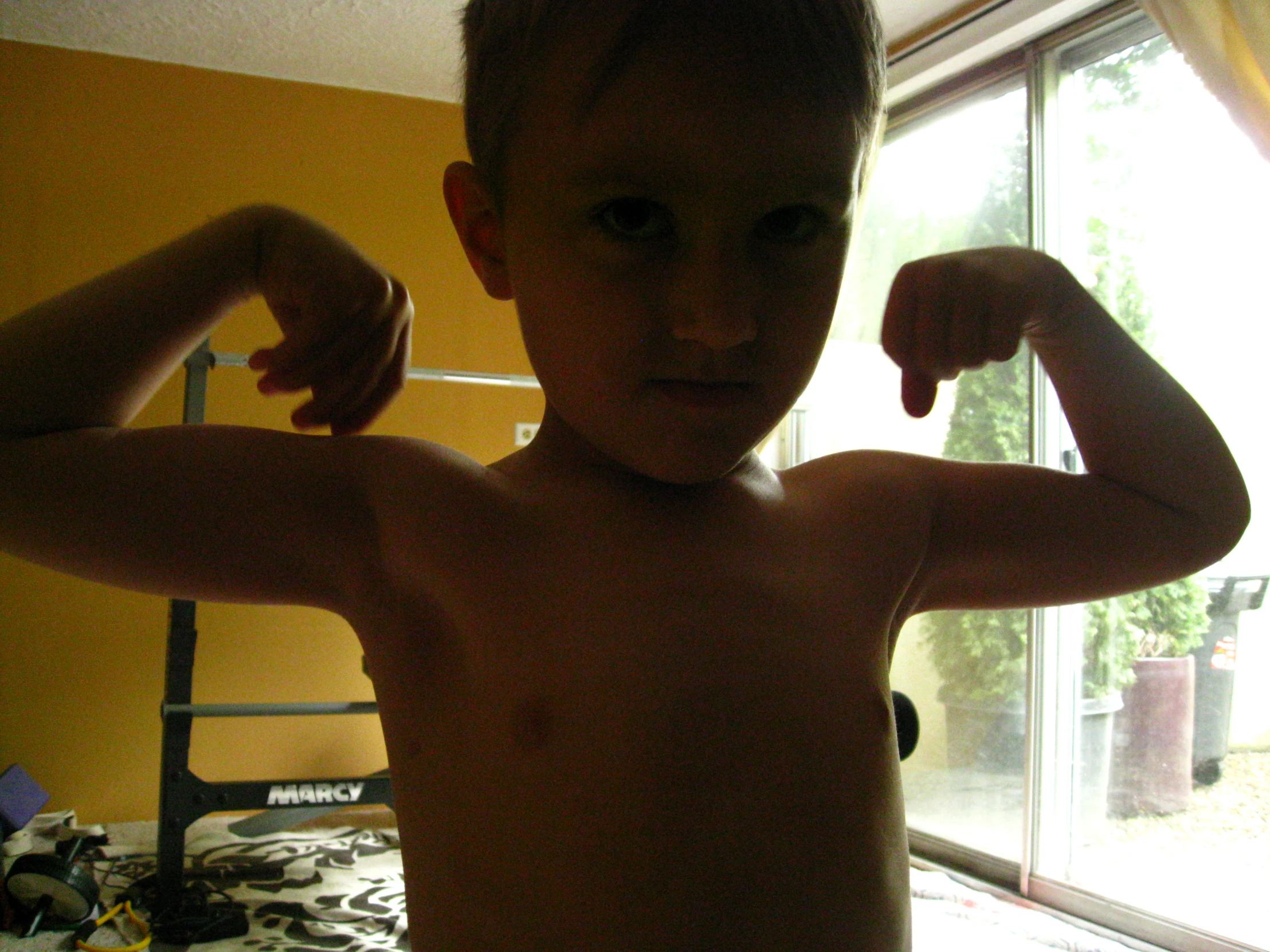 a boy with his hand up in the air and a window behind him