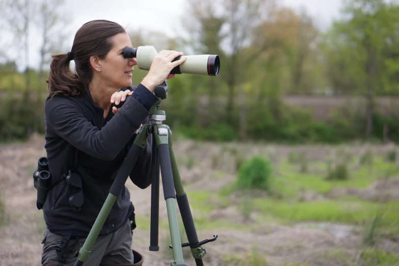 a woman standing on a grassy field with binoculars