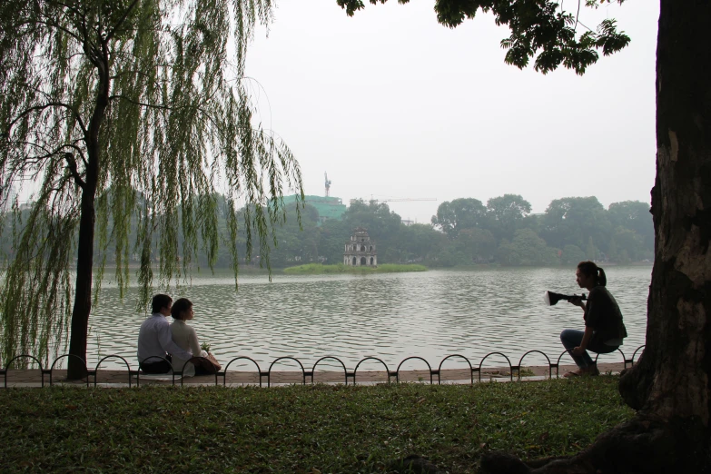 a couple of people sit on a bench near water