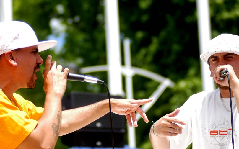 two men are singing into microphones at an outdoor concert