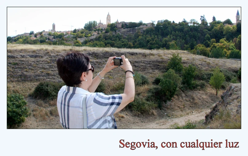 a man takes pictures of a landscape from a hill
