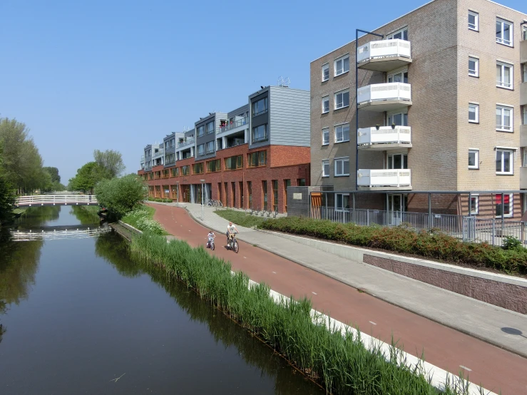 people riding bicycles on a path by the river in a city