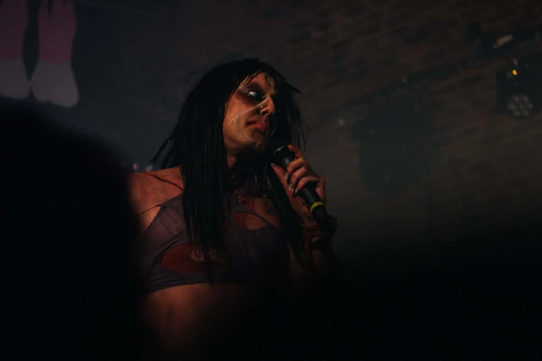 a shirtless man with dreadlocks speaking into a microphone