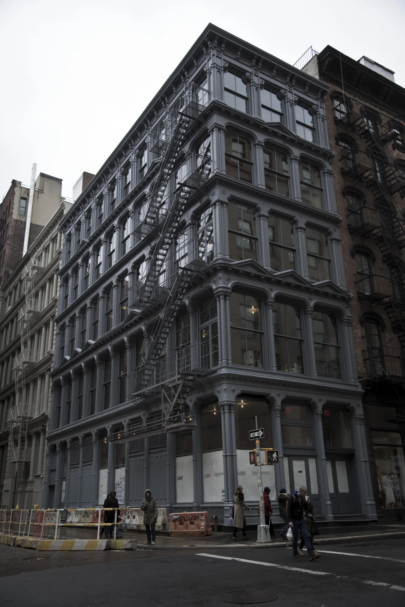 two people walk past a huge building with fire escape