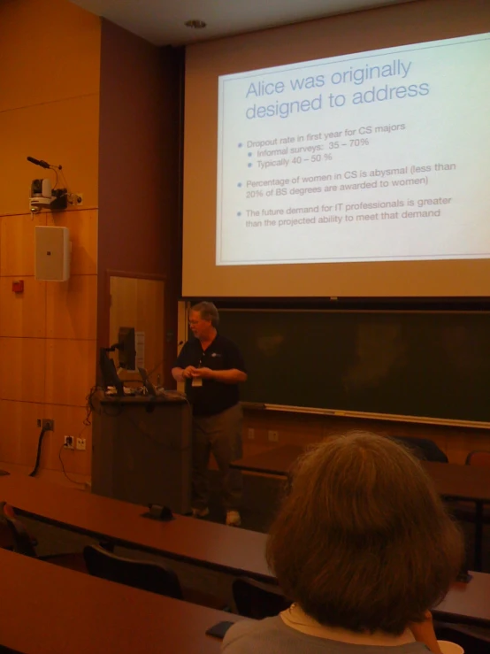 a person stands in front of a screen giving a presentation