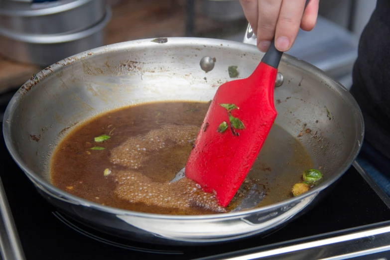 someone is stirring food in a pan with a red spatula