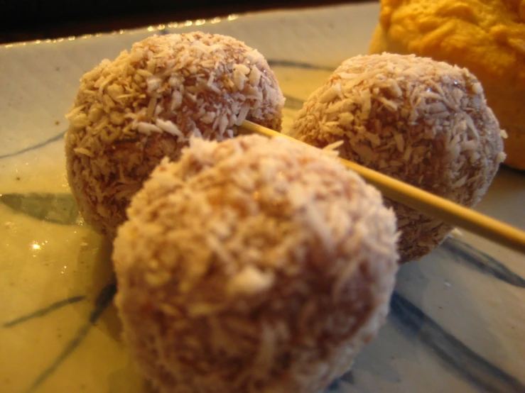 three chocolate covered balls sitting on a plate with a stick